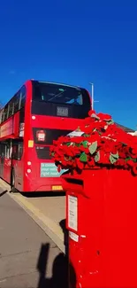 Red bus and floral display under blue sky