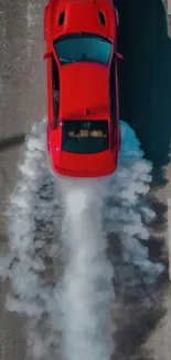 Aerial view of vibrant red car performing a burnout on a road.