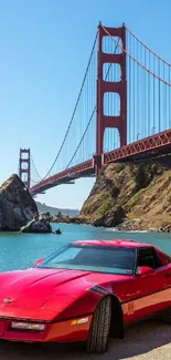 Red classic car by Golden Gate Bridge with clear skies.