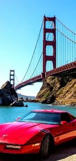Red sports car near Golden Gate under blue sky.