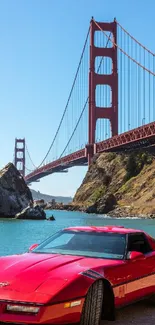 Red vintage car near Golden Gate Bridge under blue sky.