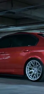 Red car parked in an underground garage with metallic wheels.