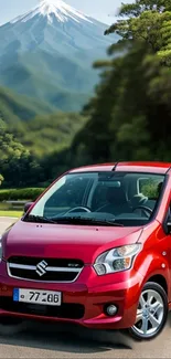 Red car traveling on a scenic mountain road with vibrant greenery.