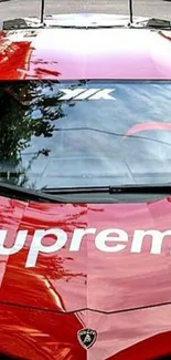 Red sports car with Supreme logo, glossy finish.