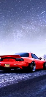 Red sports car on snowy road under a starry sky.