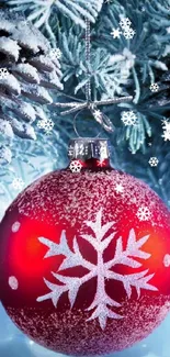 Red Christmas ornament with snowflakes on snowy pine branches.