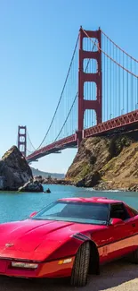 Red classic car with Golden Gate Bridge in background, clear blue sky.