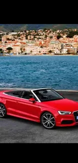 Red convertible car with seaside background.