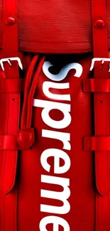 Red designer backpack with straps and white logo on mobile wallpaper.