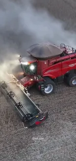 Red harvester machine working in field under sunny sky.