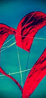 Red heart-shaped kite in blue sky wallpaper.