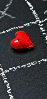 Red heart on blackboard with chalk grid pattern.