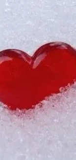 A vibrant red heart lying on white snow, creating a romantic phone wallpaper.