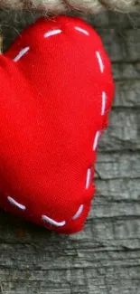 Red heart sewn on rustic wood background.