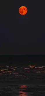 Red moon rising over dark ocean horizon