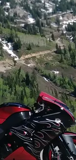 Red motorcycle with flames against green mountain backdrop.