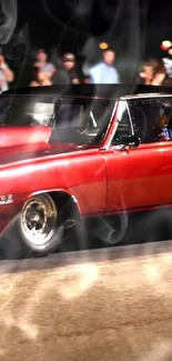 Red muscle car burning rubber at night with spectators watching.