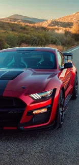 Red Mustang driving on a scenic mountain road.