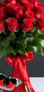 A bouquet of red roses with a red ribbon and a butterfly.