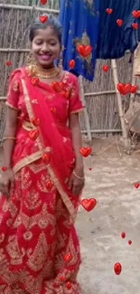 Woman in red saree with heart motifs on a mobile wallpaper.