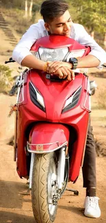 Red scooter with a young man in a scenic countryside setting.