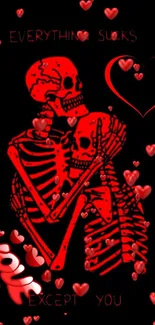 Red skeletons embracing with hearts on dark wallpaper.