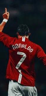 Soccer player celebrating in red jersey with arm raised.