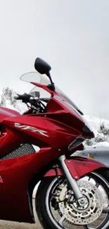 Red sports bike on a snowy road with mountains in the background.