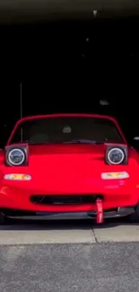 Red sports car with raised headlights in garage.