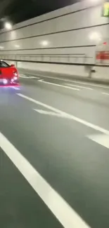 Red sports car speeding through a tunnel at night.