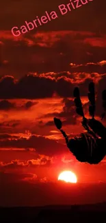 Red sunset with black handprint silhouette on wallpaper.