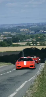 Red supercars speeding through scenic countryside on an open road