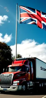 Red truck on highway beneath Union Jack flying against blue sky.