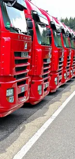 Red trucks lined up along a scenic road for a striking mobile wallpaper.