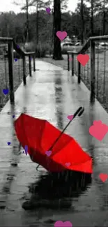 Red umbrella on a wet bridge with colorful hearts in black and white setting.