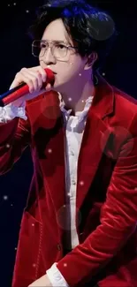 Performer in a red velvet jacket on stage, holding a red microphone.