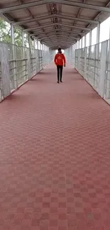 Person walks on red tiled urban walkway bridge.