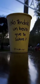 Yellow coffee cup with message in reflective outdoor setting.