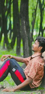 Man sitting against a tree in a forest, reflecting in nature.