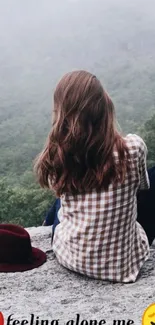 Girl sitting alone on a misty cliff with scenic background.