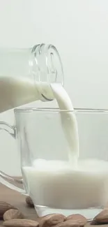 Almond milk being poured into a clear glass on a wooden table.