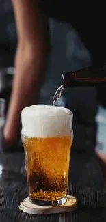 Mobile wallpaper of beer being poured into a glass with a rich, frothy head.