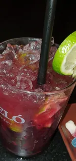 Berry cocktail with lime garnish and ice cubes.