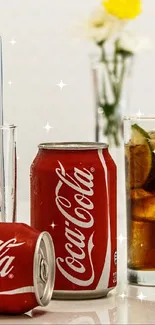 Coca-Cola cans with glasses and straws on a white tabletop.