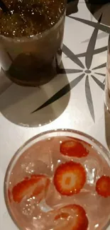 Close-up of cocktails with strawberries and ice on a stylish table.