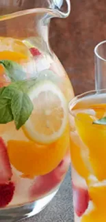 Clear pitcher with citrus fruit infusion and strawberries.