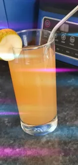 Glass of orange juice with metal straw on countertop.