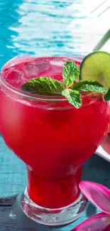 Red tropical drink with lime and mint by the pool.