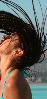 Woman flipping hair in a sunny poolside setting, enjoying summer.