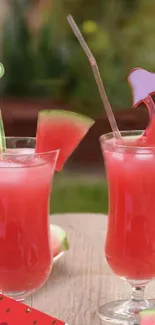 Two pinkish-red watermelon drinks with fruit slices and straws.